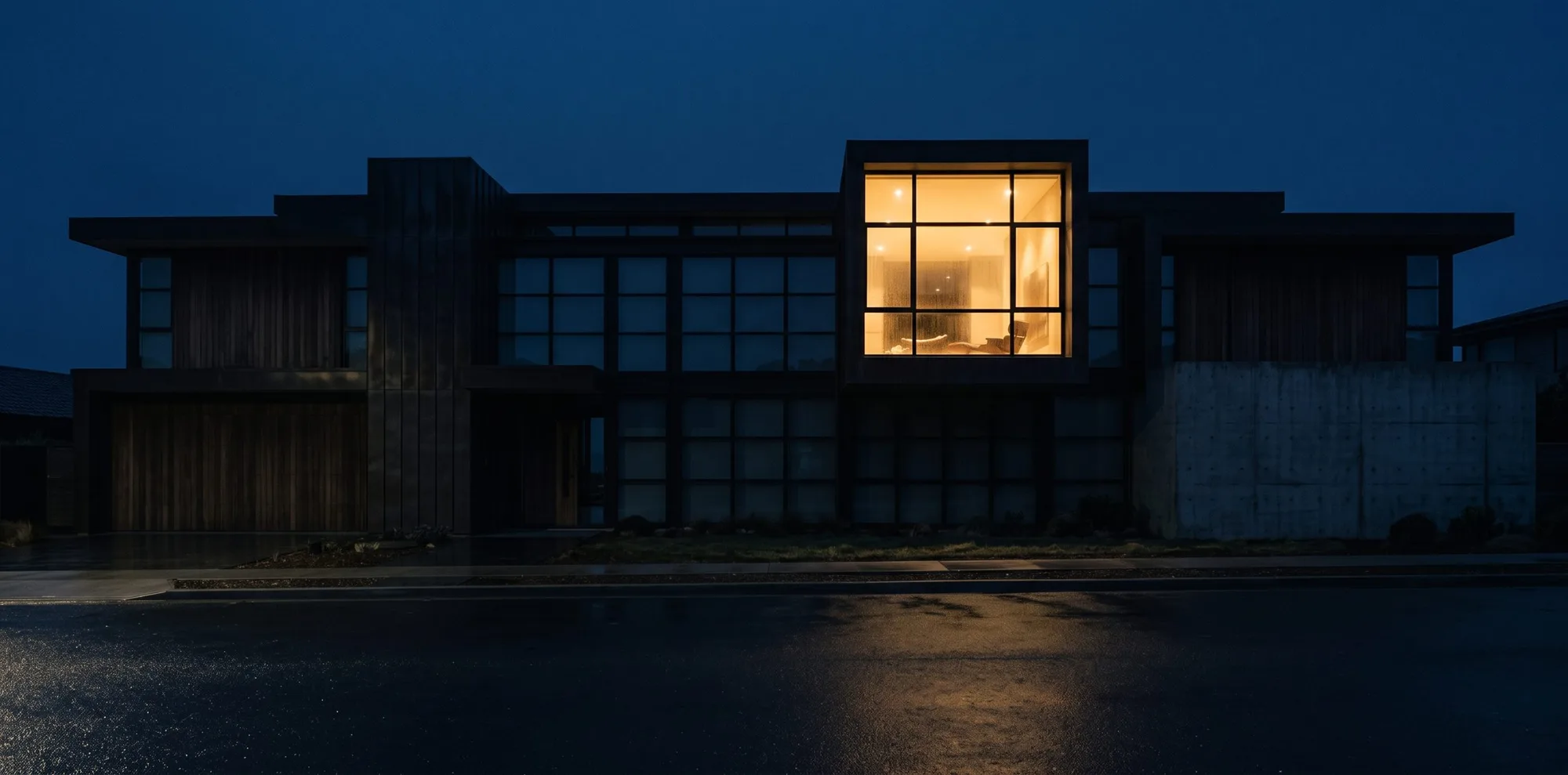 Fachada noturna, quase escura, com uma única luz acesa.